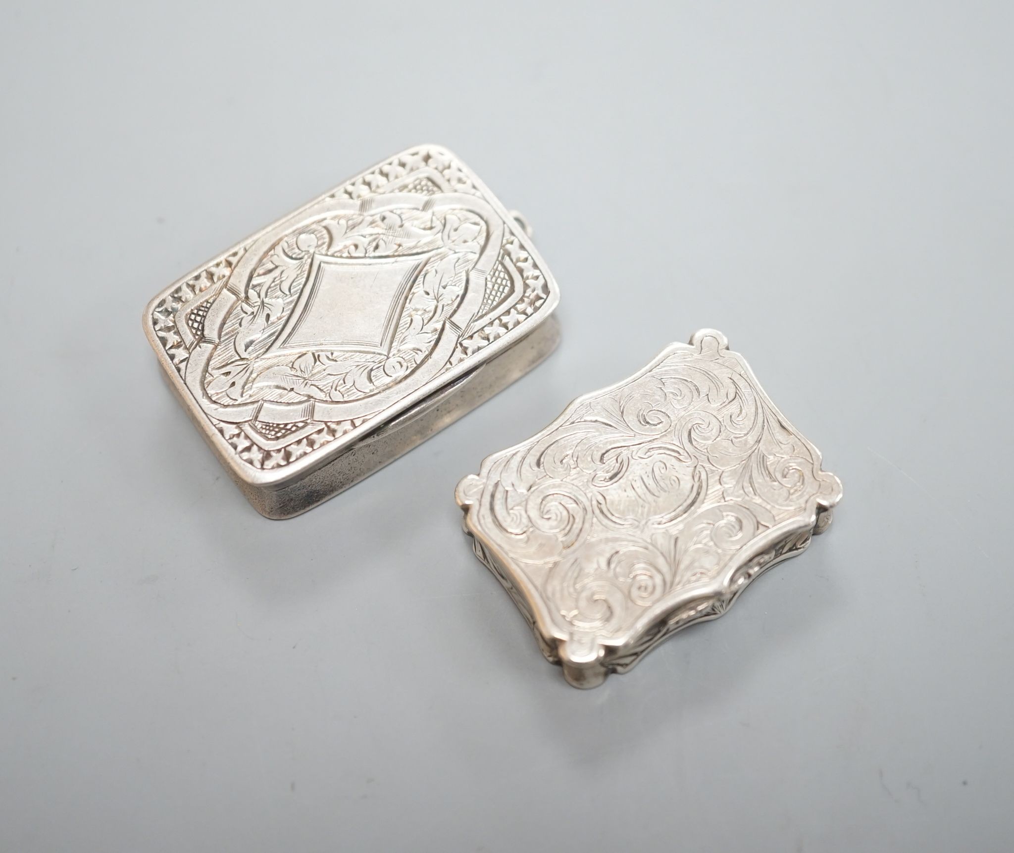 An early Victorian engraved silver shaped rectangular vinaigrette, by Nathaniel Mills, Birmingham, 1844, 31mm and a later silver vinaigrette by George Unite.